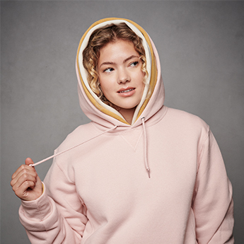 Female model with white fleece hoodie wrapped around shoulders. 